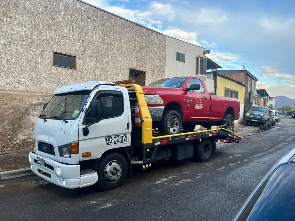 Grúa de plataforma Hyundai Mighty de Grúa Urgente transportando una camioneta Dodge Ram Grúa de emergencia 24 horas en el gran Santiago