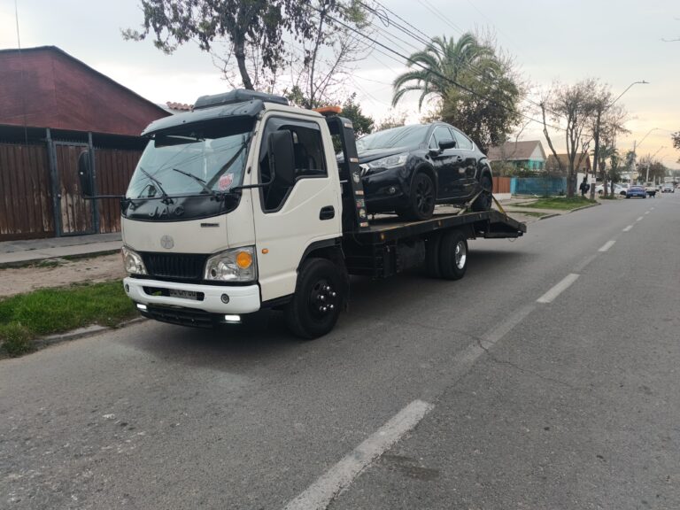 Grúa de plataforma de Grúa Urgente remolcando un automóvil oscuro en la calle Grúa de emergencia 24 horas en el gran Santiago
